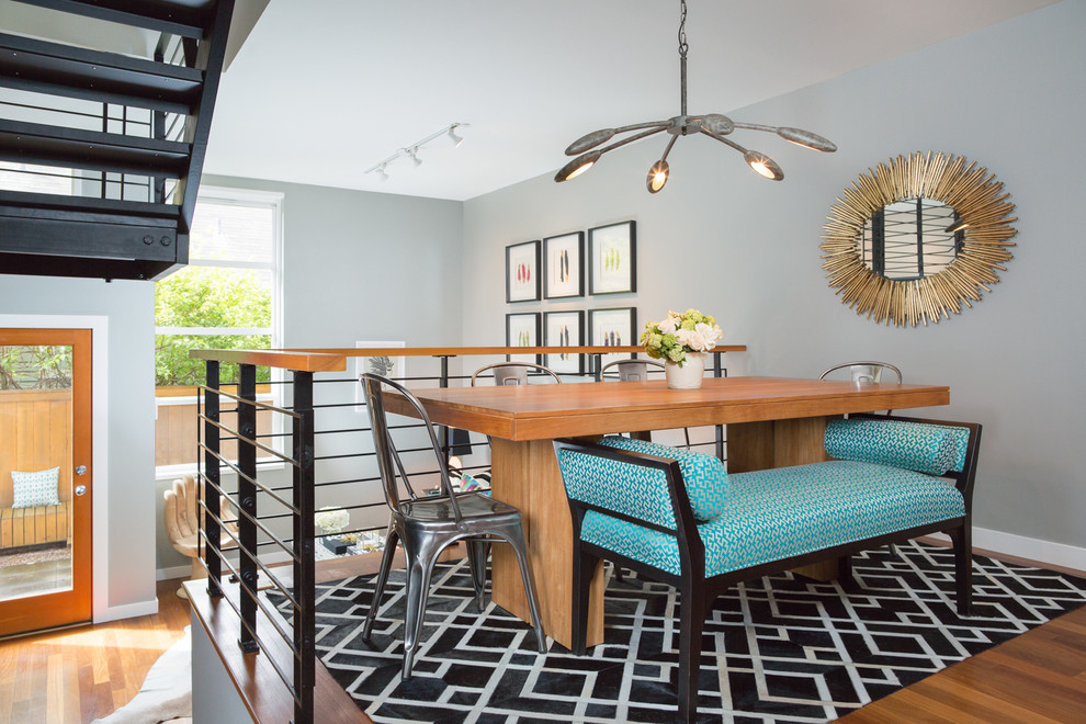 Cette image montre une salle à manger ouverte sur la cuisine design de taille moyenne avec un mur blanc et un sol en bois brun.