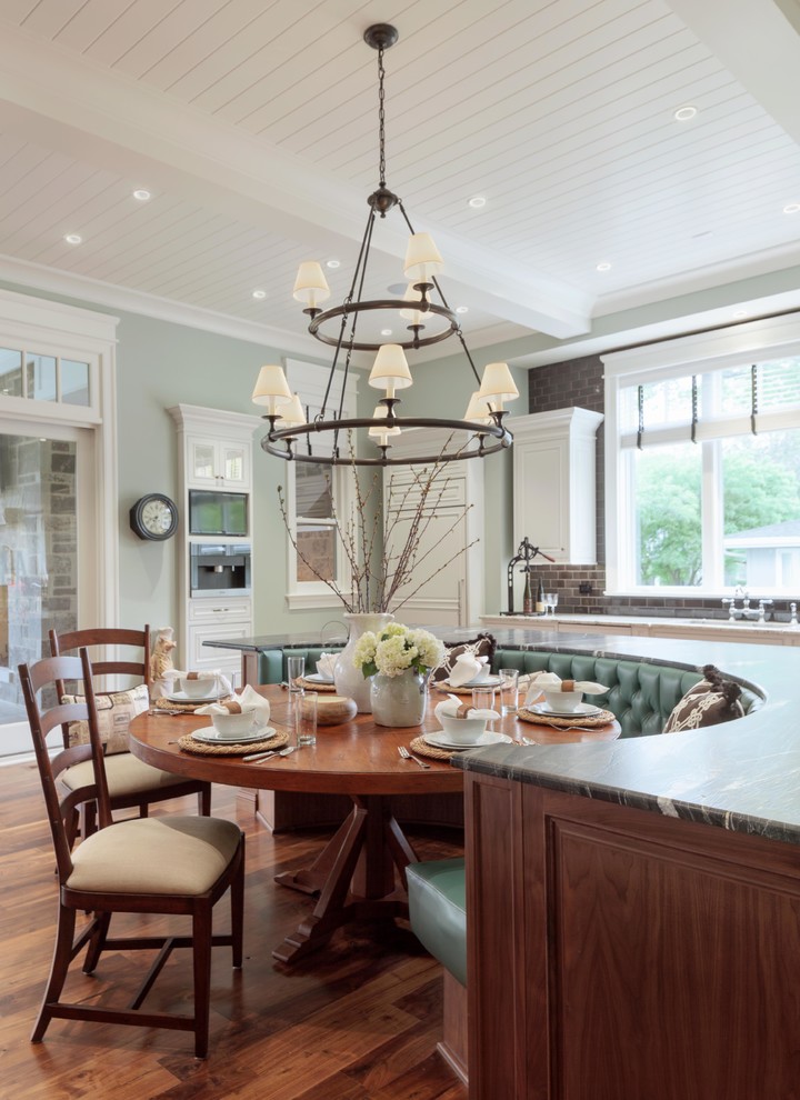 Immagine di una sala da pranzo aperta verso la cucina tradizionale con pareti verdi e pavimento in legno massello medio