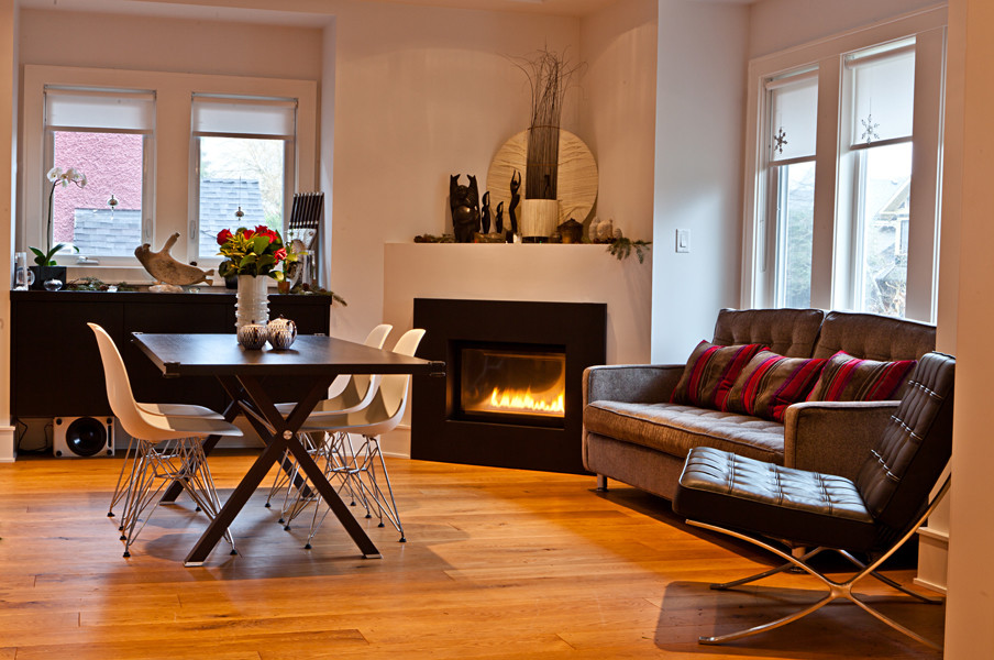 バンクーバーにある高級な中くらいなコンテンポラリースタイルのおしゃれなLDK (白い壁、無垢フローリング、コーナー設置型暖炉、金属の暖炉まわり、茶色い床) の写真
