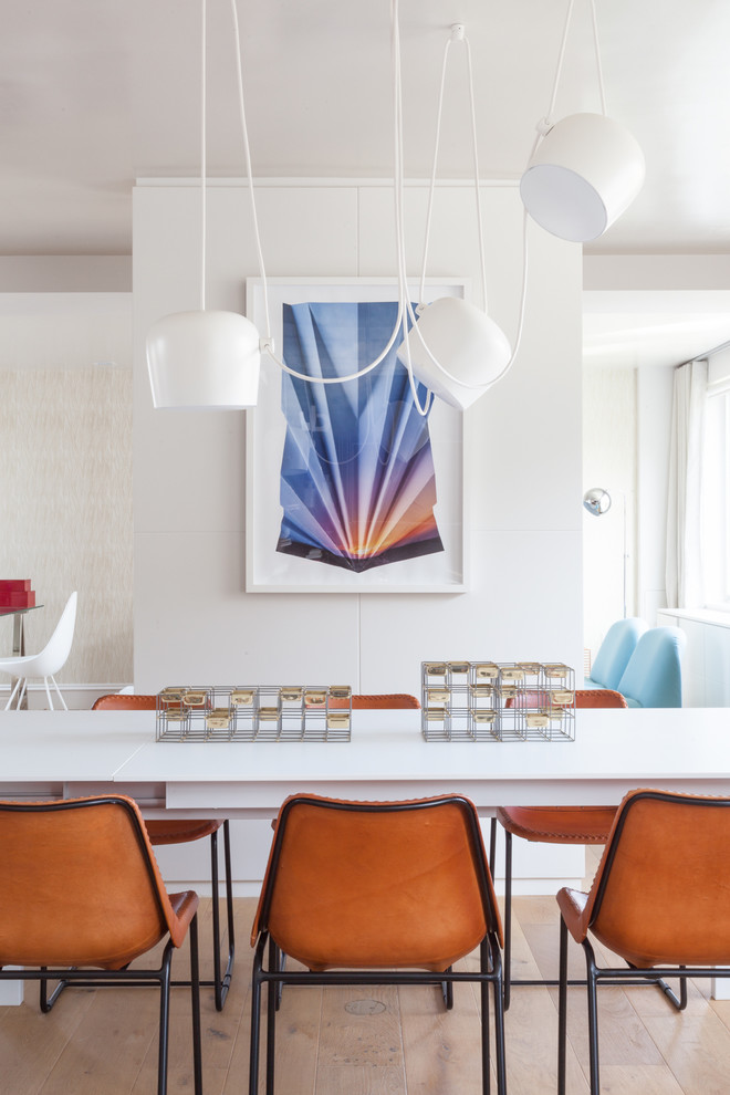 Immagine di una sala da pranzo aperta verso la cucina design di medie dimensioni con pareti bianche, parquet chiaro e nessun camino