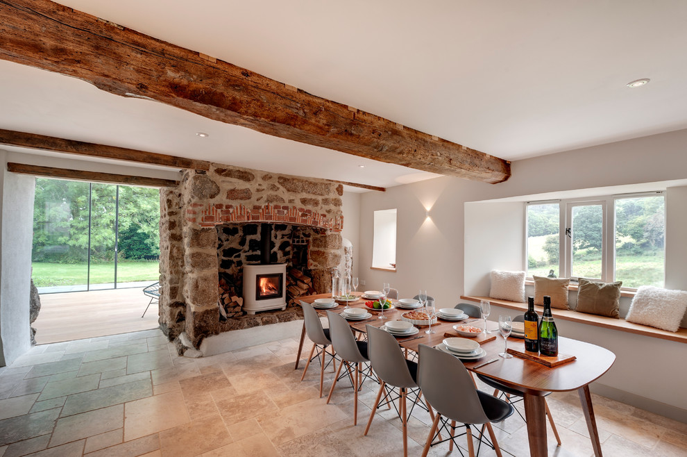 Dining room - cottage dining room idea in Devon with white walls, a wood stove and a stone fireplace