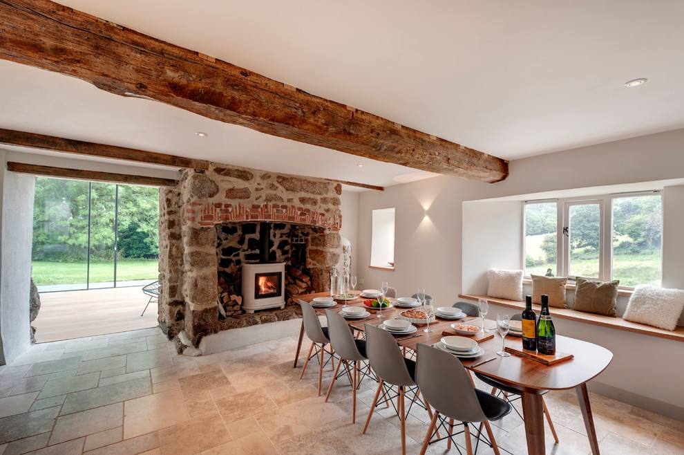 Foto di una grande sala da pranzo country con pareti bianche, stufa a legna e cornice del camino in pietra