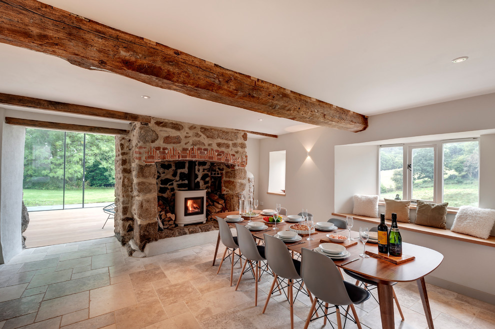 Inspiration for a large open plan dining room in Devon with white walls, limestone flooring, a wood burning stove and a stone fireplace surround.
