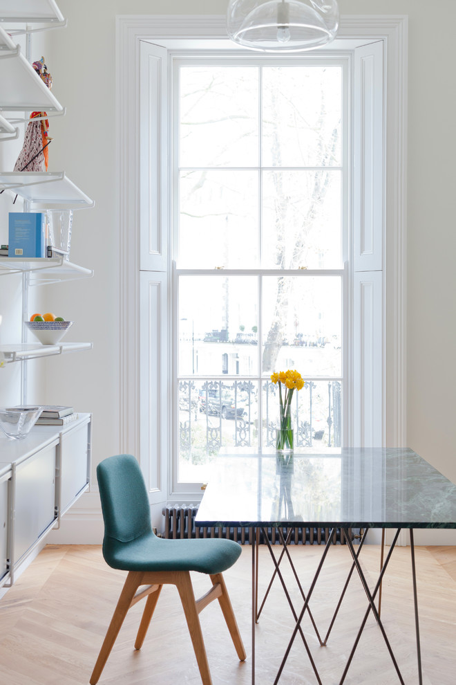 Photo of a small contemporary enclosed dining room in London with white walls and light hardwood flooring.
