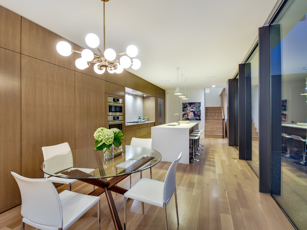 Cette image montre une salle à manger ouverte sur la cuisine design avec un mur blanc, parquet clair et un sol marron.