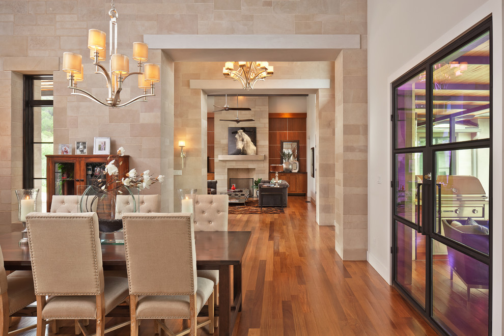 Medium sized classic kitchen/dining room in Austin with grey walls, medium hardwood flooring, a standard fireplace and a stone fireplace surround.