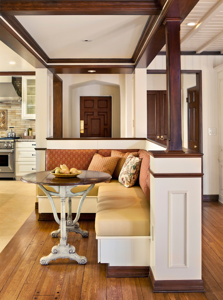 Cette photo montre une salle à manger ouverte sur la cuisine chic avec un mur blanc et un sol en bois brun.