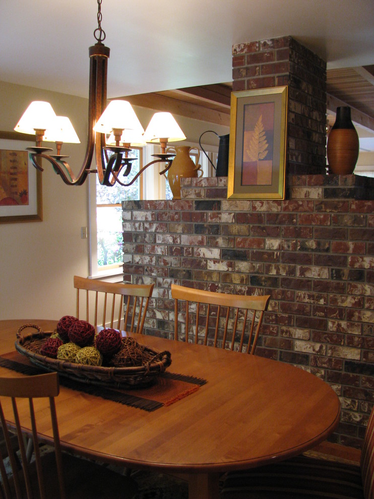 Modelo de comedor de cocina clásico renovado de tamaño medio con paredes amarillas, suelo de madera clara, todas las chimeneas y marco de chimenea de ladrillo