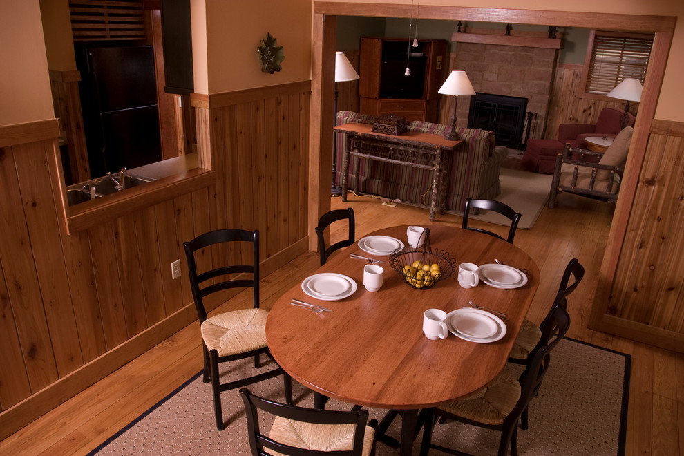 Idées déco pour une salle à manger ouverte sur la cuisine classique de taille moyenne avec un mur beige, un sol en bois brun, une cheminée standard et un manteau de cheminée en pierre.