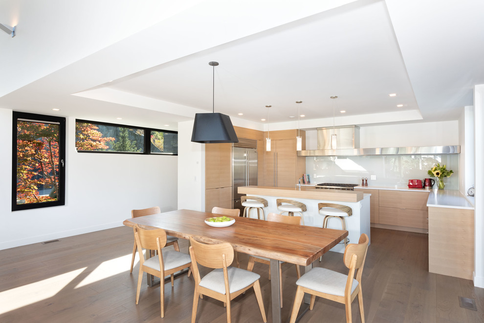 Exemple d'une salle à manger ouverte sur la cuisine tendance avec un mur blanc, parquet foncé et un sol marron.
