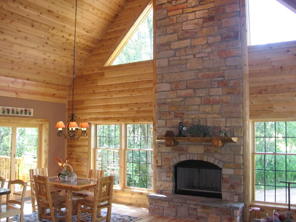 Aménagement d'une grande salle à manger ouverte sur le salon montagne avec parquet clair, une cheminée standard et un manteau de cheminée en pierre.