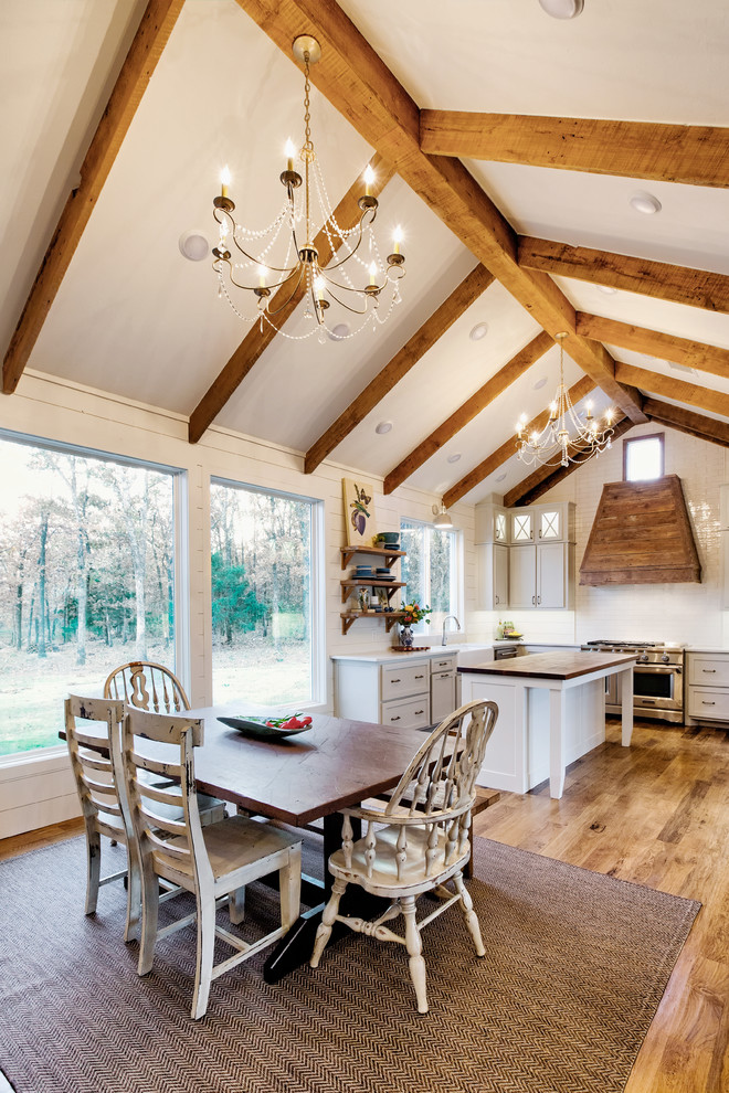 Idee per una sala da pranzo aperta verso la cucina country con pareti bianche, pavimento in legno massello medio e pavimento marrone
