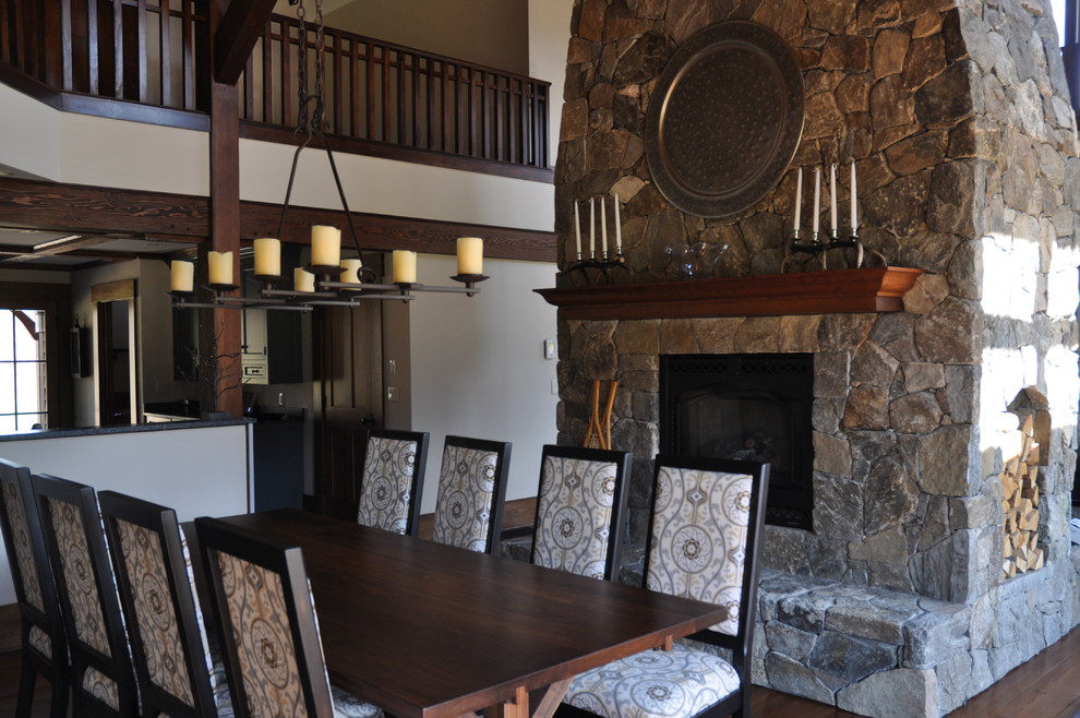 Idée de décoration pour une grande salle à manger ouverte sur le salon tradition avec parquet foncé, une cheminée double-face, un manteau de cheminée en pierre et un mur blanc.