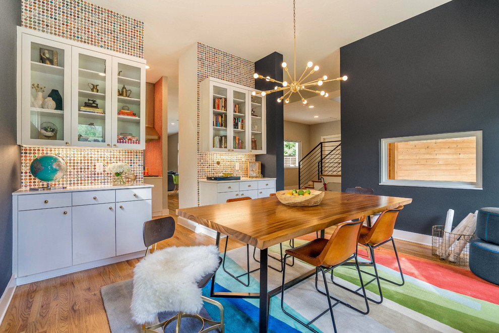 This is an example of an eclectic dining room in Dallas with multi-coloured walls, medium hardwood flooring and brown floors.