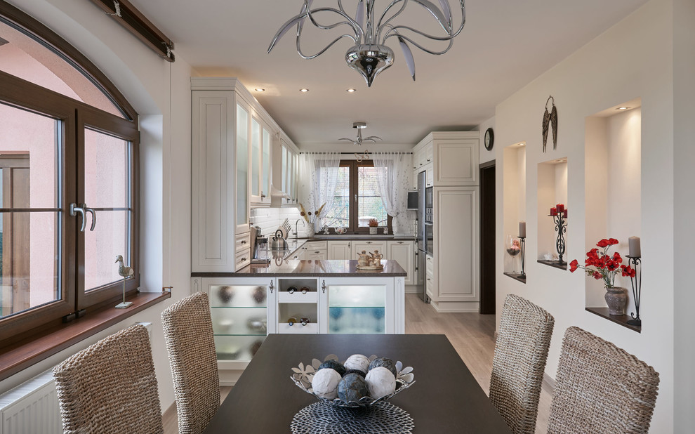 На фото: кухня-столовая среднего размера в классическом стиле с белыми стенами, полом из фанеры, стандартным камином и бежевым полом