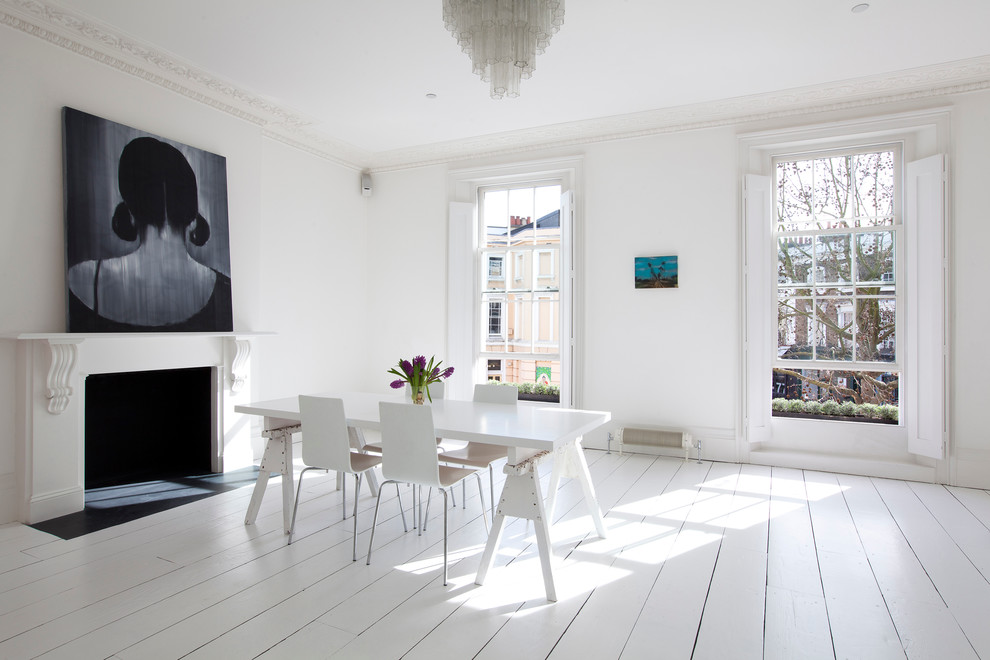 Cette image montre une salle à manger nordique avec un mur blanc, parquet peint, une cheminée standard et un sol blanc.