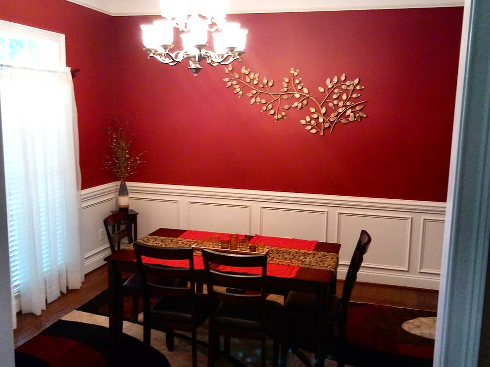 Inspiration pour une petite salle à manger design fermée avec un mur rouge, un sol en bois brun, aucune cheminée et un sol marron.