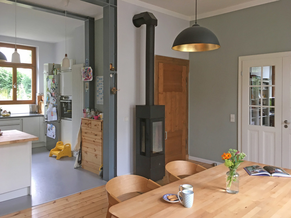 Idee per una sala da pranzo design con pareti grigie, parquet chiaro e stufa a legna