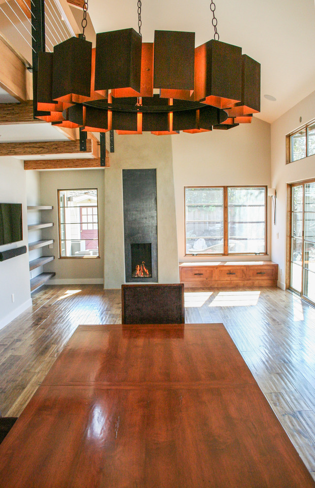 Cette image montre une salle à manger ouverte sur le salon design de taille moyenne avec un sol en bois brun et un manteau de cheminée en métal.