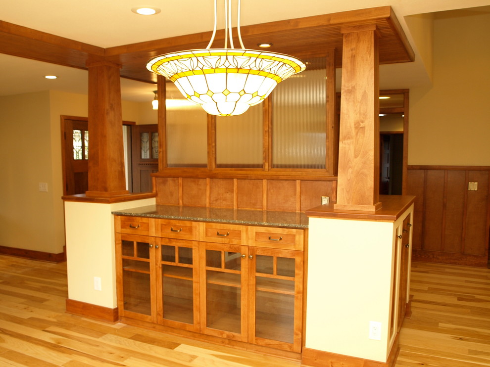 Réalisation d'une salle à manger craftsman avec un sol en bois brun, une cheminée standard et un manteau de cheminée en bois.