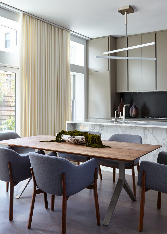 Immagine di una sala da pranzo aperta verso la cucina minimalista di medie dimensioni con pareti bianche, pavimento in legno massello medio e pavimento marrone