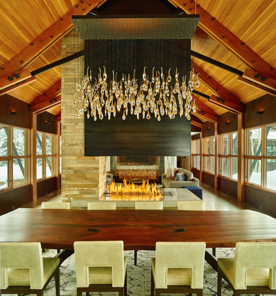 Idée de décoration pour une très grande salle à manger ouverte sur le salon design avec sol en béton ciré, une cheminée double-face et un manteau de cheminée en métal.