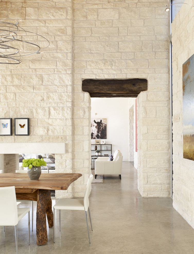 Mediterranean dining room in Austin with a two-sided fireplace and a stone fireplace surround.