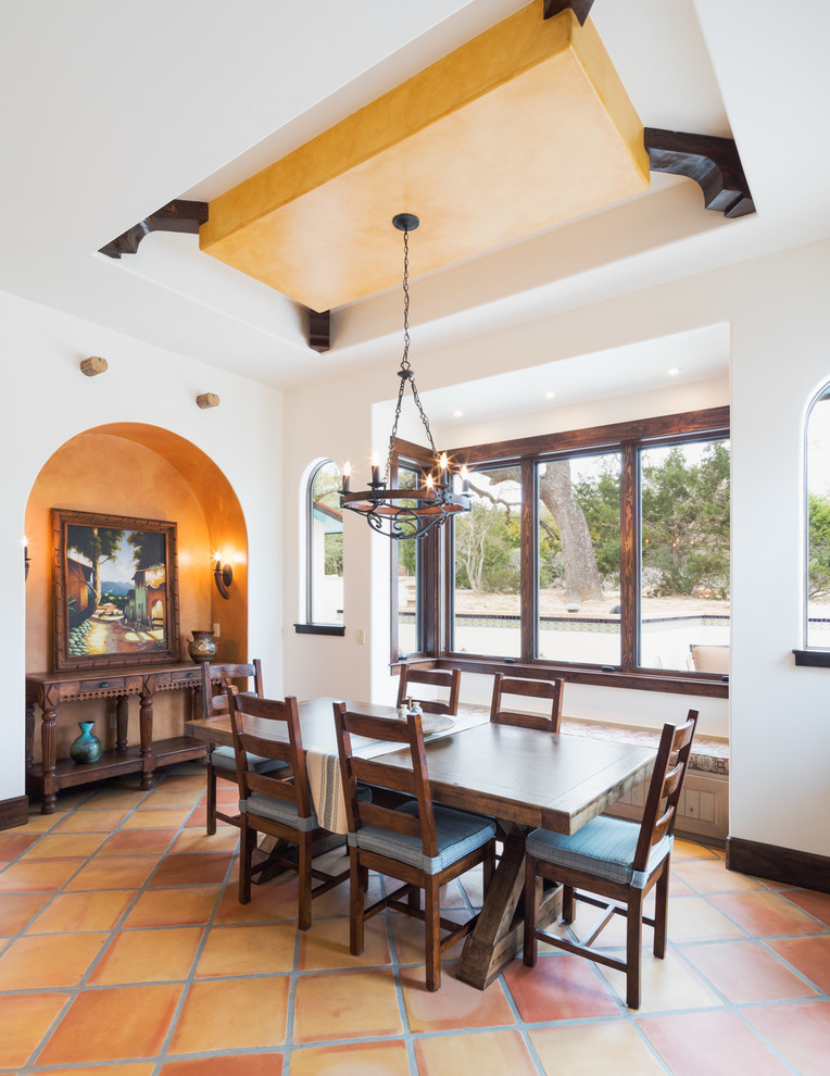 Example of a large tuscan terra-cotta tile and brown floor kitchen/dining room combo design in Austin with multicolored walls and no fireplace