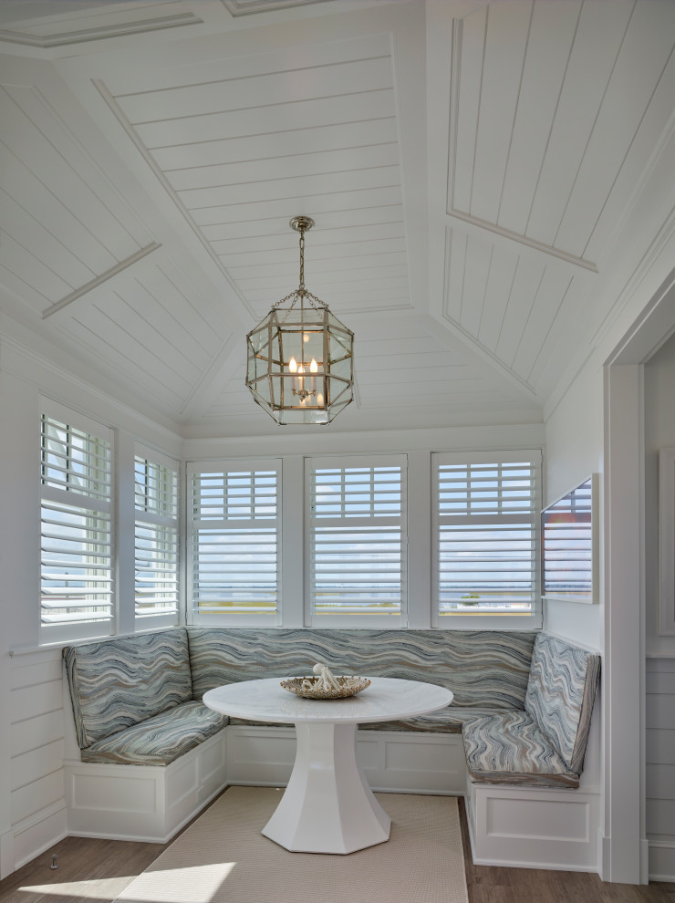 Large coastal dining room in Philadelphia with white walls, medium hardwood flooring, a vaulted ceiling and wainscoting.
