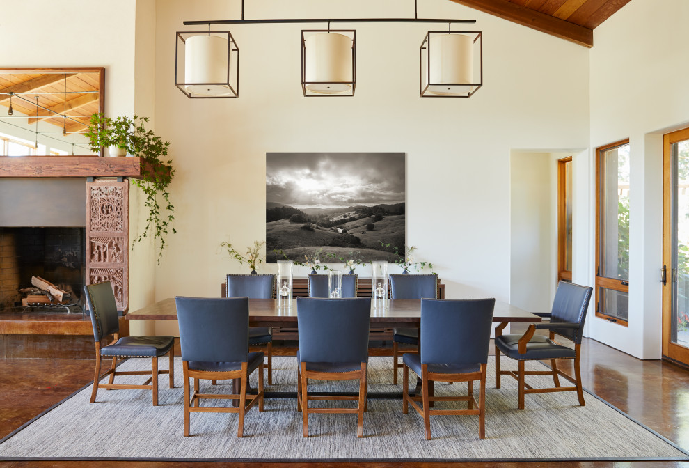 Inspiration pour une grande salle à manger ouverte sur le salon chalet avec un mur blanc, une cheminée standard, sol en béton ciré, un sol marron, un plafond voûté et un plafond en bois.