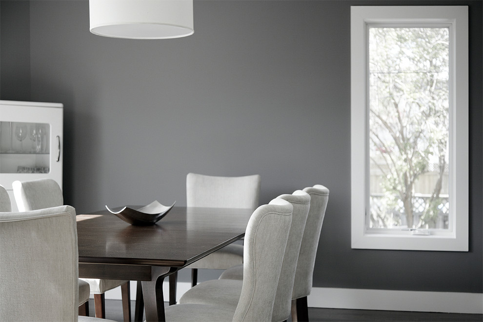 Cette image montre une salle à manger ouverte sur la cuisine minimaliste de taille moyenne avec un mur gris, parquet foncé et aucune cheminée.