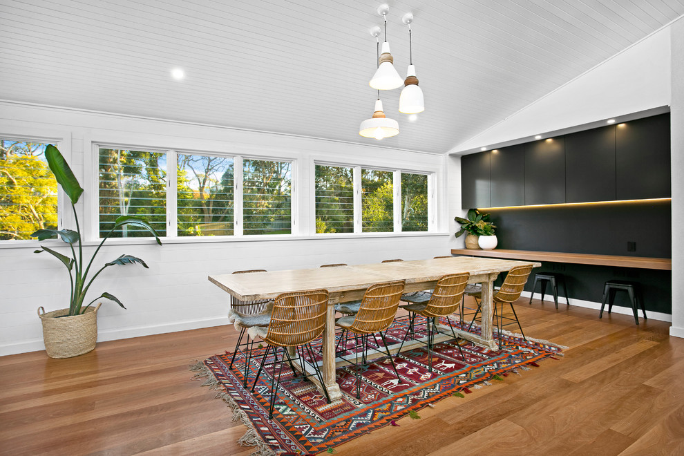 Imagen de comedor actual abierto con paredes blancas y suelo de madera en tonos medios