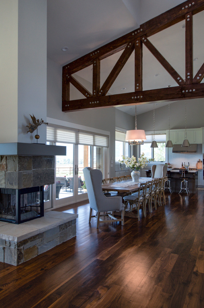 Large country kitchen/dining room in Salt Lake City with grey walls, dark hardwood flooring, a two-sided fireplace and a stone fireplace surround.