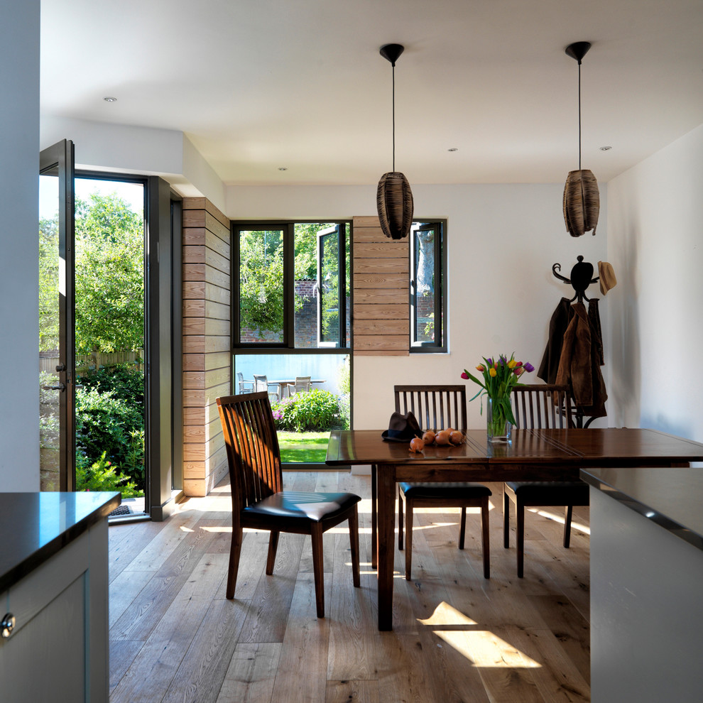 Inspiration for a large contemporary kitchen/dining room in London with white walls and light hardwood flooring.