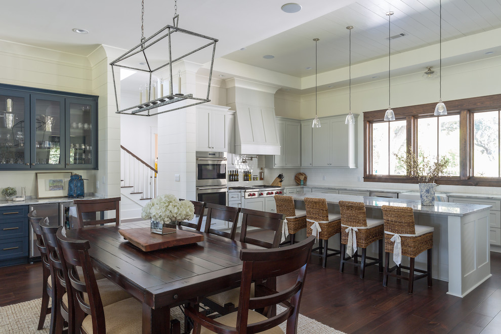 Ispirazione per una sala da pranzo aperta verso la cucina stile marinaro con pareti bianche, parquet scuro e pavimento marrone