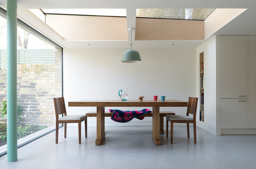 Diseño de comedor moderno de tamaño medio cerrado con paredes blancas, suelo de cemento y suelo gris