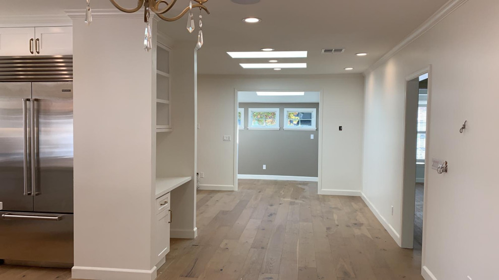 Photo of a large modern kitchen/dining room in Los Angeles with white walls, light hardwood flooring and beige floors.