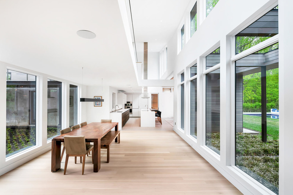 Foto di una grande sala da pranzo aperta verso la cucina contemporanea con pareti bianche, parquet chiaro, nessun camino e pavimento beige