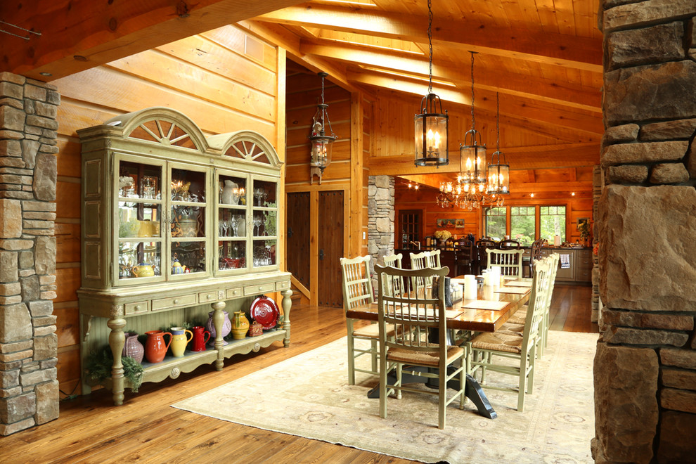 Foto di una sala da pranzo aperta verso il soggiorno stile rurale di medie dimensioni con pavimento in legno massello medio e cornice del camino in pietra