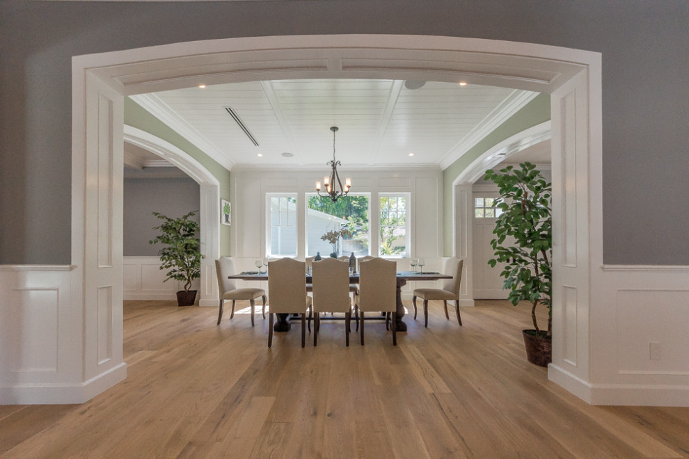 Large traditional enclosed dining room in Los Angeles with green walls, medium hardwood flooring, brown floors, a coffered ceiling and wainscoting.