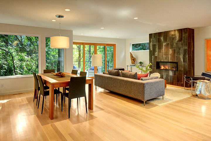 Photo of a medium sized modern open plan dining room in Seattle with white walls, light hardwood flooring, a standard fireplace, a tiled fireplace surround and beige floors.