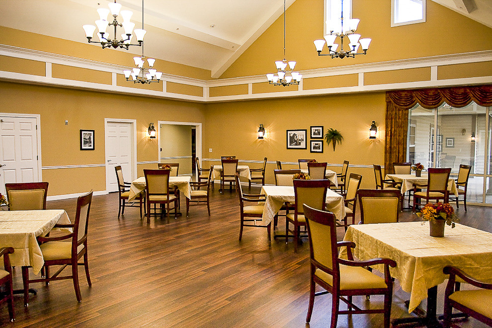 Immagine di un'ampia sala da pranzo aperta verso il soggiorno design con pareti gialle, pavimento in vinile e pavimento marrone