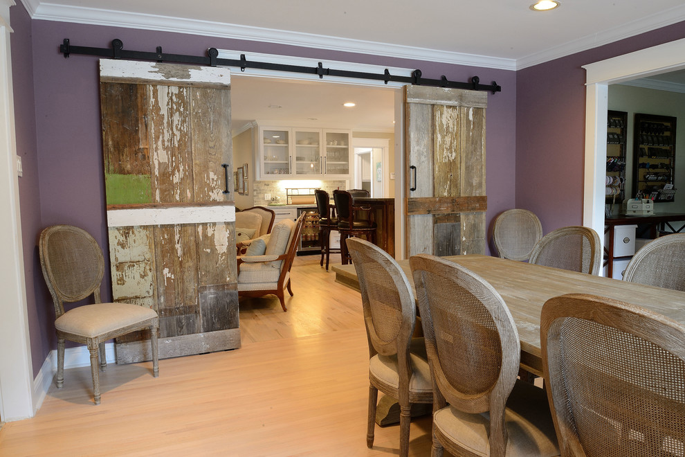 Foto di una grande sala da pranzo aperta verso la cucina country con pareti viola, parquet chiaro e nessun camino