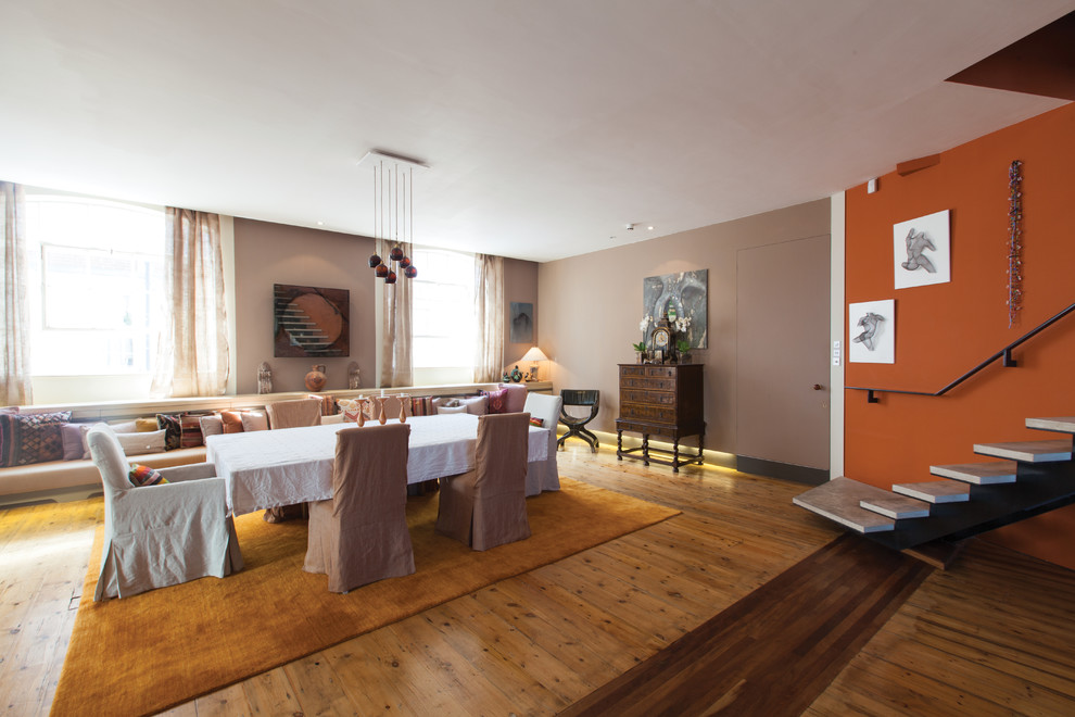 Immagine di un'ampia sala da pranzo aperta verso il soggiorno bohémian con pareti beige e pavimento in legno massello medio