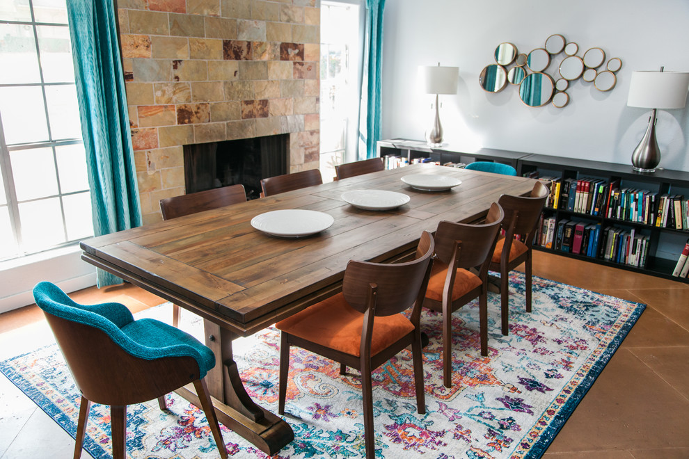 Aménagement d'une salle à manger ouverte sur la cuisine rétro de taille moyenne avec un mur bleu, sol en béton ciré, une cheminée standard, un manteau de cheminée en pierre et un sol marron.