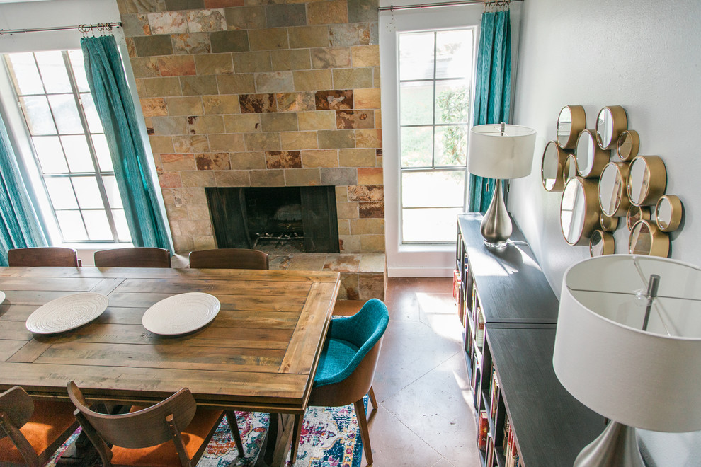 Idée de décoration pour une salle à manger ouverte sur la cuisine vintage de taille moyenne avec un mur bleu, sol en béton ciré, une cheminée standard, un manteau de cheminée en pierre et un sol marron.