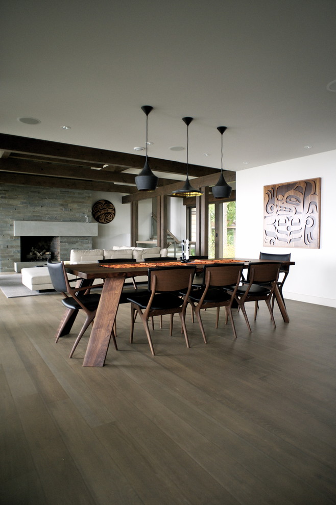 Aménagement d'une grande salle à manger ouverte sur le salon contemporaine avec un mur blanc et un sol en bois brun.