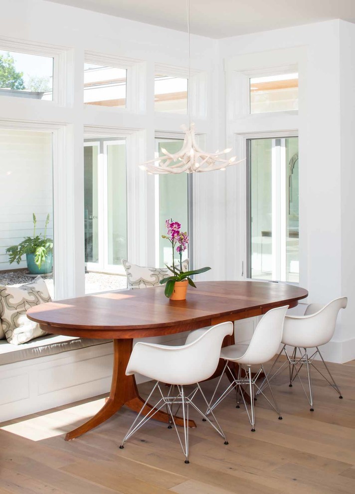 Cette image montre une salle à manger ouverte sur la cuisine design de taille moyenne avec un mur blanc, un sol en bois brun, aucune cheminée et un sol marron.