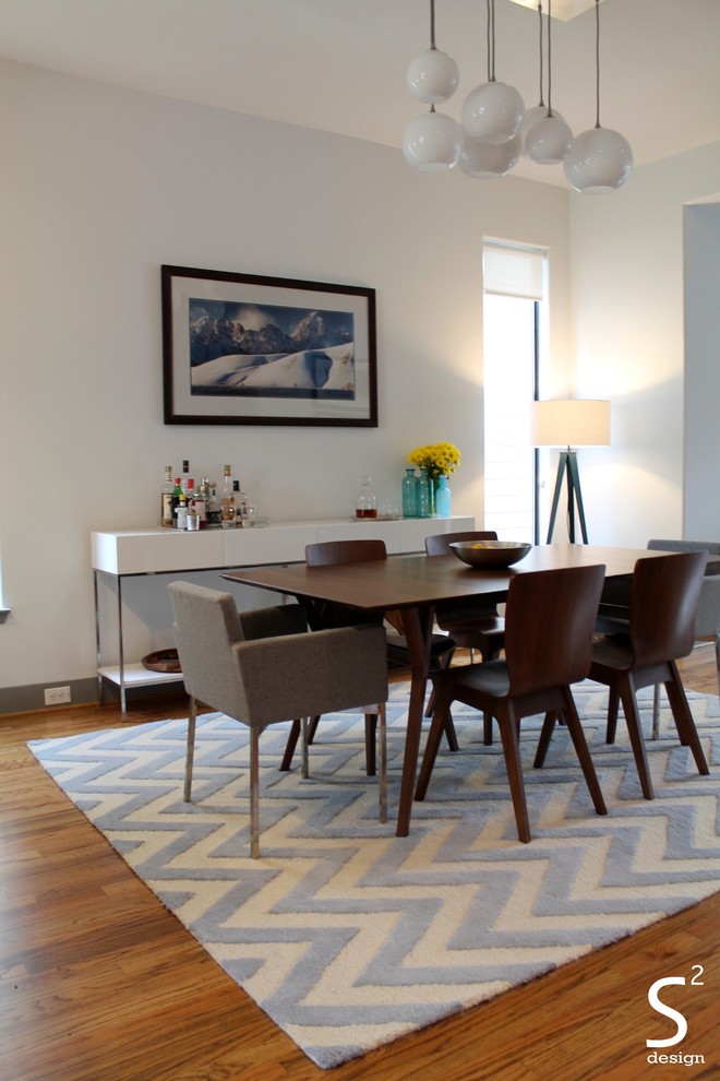 Idée de décoration pour une salle à manger ouverte sur le salon vintage de taille moyenne avec un sol en bois brun et un mur blanc.