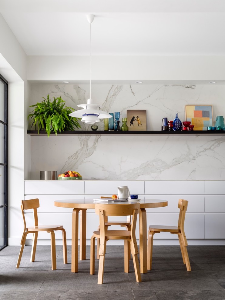 Réalisation d'une grande salle à manger ouverte sur la cuisine design avec un sol en calcaire et un mur blanc.